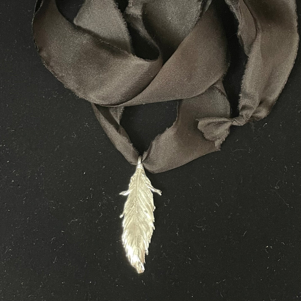 Feather pendant on silk ribbon