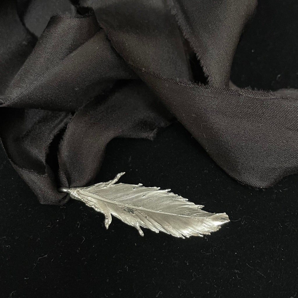Feather pendant on silk ribbon